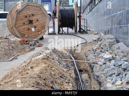 Holz- Spule der elektrischen Kabel und optische Fasern im graben Graben auf der Baustelle Stockfoto