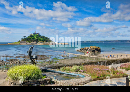 21. Juni 2018: Marazion, Cornwall, UK-St Michael's Mount von Marazion, mit einem Delphin Brunnen im Vordergrund. Menschen können gesehen werden ihren Weg Stockfoto