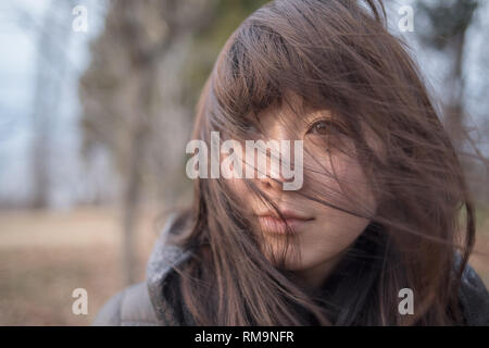 Außerhalb der Szene in der Natur mit schönen und netten jungen Frau und ihr braunes Haar im Wind der Betrachtung der Landschaft. Japan. Stockfoto