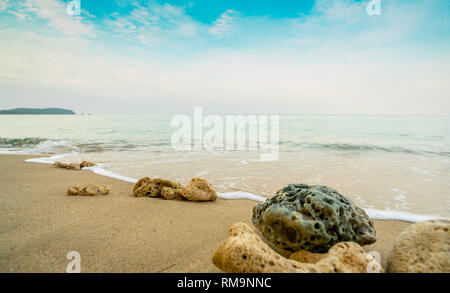 Korallen auf Sand Strand am Meer mit blauem Himmel und weißen Wolken. Sommer Urlaub im tropischen Paradies Strand Konzept. Welligkeit von Spritzwasser am Sandstrand. Stockfoto