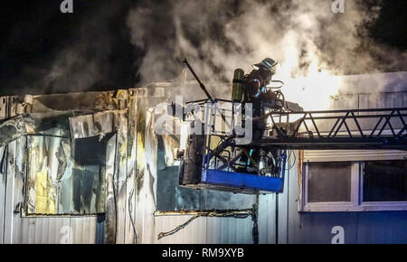 14. Februar 2019, Baden-Wuerttemberg, Weil der Stadt: ein Feuerwehrmann löscht ein Feuer in einem Asylbewerber Schutz von einem drehleiter. Über 100 Feuerwehrleute löschten die Flammen. Der Rettungsdienst kümmerte sich um die mehr als 20 obdachlose Bewohner. (Dpa: "Verletzte bei Brand in Asylbewerberheim Unterkunft - große Feuerwehr Einsatz" von 14.02.2019) Foto: Dettenmeyer/SDMG/dpa Stockfoto