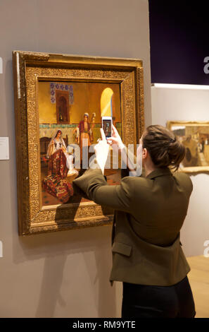 London, Großbritannien. 14 Feb, 2019. Bonhams Fotoshooting für 19. Jahrhundert europäischer, viktorianischen UND BRITISCHEN impressionistischer Kunst Verkauf fand bei Bonhams New Bond Street. Ein Mitarbeiter nimmt ein Foto mit Ihrem Handy von RUDOLF ERNST, Österreichische, 1854-1932) Der Teppich Entscheidungsträger auf £ 30.000 - 50.000 geschätzt. Der Verkauf findet am 20. Februar um 14:00 Uhr. Credit: Keith Larby/Alamy leben Nachrichten Stockfoto