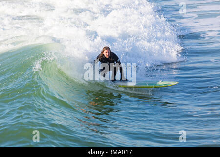 Bournemouth, Dorset, Großbritannien. 14 Feb, 2019. UK Wetter: schön warmen sonnigen Tag in Bournemouth wie Besucher Kopf an der Küste der Sonne in Bournemouth Strände am Valentines Tag zu genießen. Surfer in der Sonne. Auf Surfbrett Reiten die Wellen Surfer. Credit: Carolyn Jenkins/Alamy leben Nachrichten Stockfoto