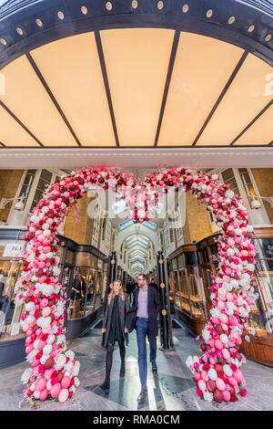 London, Großbritannien. 14. Feb 2019. Ein paar Pass durch eine riesige Valentinstag Herz heißt Menschen im Norden Ende der Burlington Arcade. Credit: Guy Bell/Alamy leben Nachrichten Stockfoto