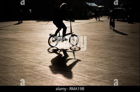 Hannover, Deutschland. 14 Feb, 2019. Ein Mann reitet ein Faltrad über den Kröpcke, einem zentralen Platz in der Innenstadt, im hellen Gegenlicht der Sonne. Credit: Julian Stratenschulte/dpa/Alamy leben Nachrichten Stockfoto