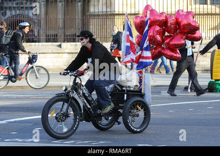 London, Großbritannien. 14 Feb, 2019. Ein Pro Brexit Demonstrant wird gesehen, mit dem Fahrrad außerhalb der Häuser des Parlaments mit herzförmigen Luftballons und Union Jack Fahnen befestigt. MPs eingestellt sind heute zu diskutieren und über die nächsten Schritte zur Brexit Prozess später Abstimmung als Premierminister Theresa May weiterhin versuchen, ihr Angebot durch das Parlament zu erhalten. Credit: Dinendra Haria/SOPA Images/ZUMA Draht/Alamy leben Nachrichten Stockfoto