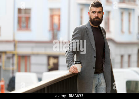 Man bärtige hipster Kaffee trinken Pappbecher. Noch ein Schluck Kaffee. Stadt Lebensstil. Geschäftsmann gepflegt aussehen genießen Sie Kaffee Pause aus Business Center im städtischen Hintergrund. Entspannen und erholen Sie sich. Stockfoto