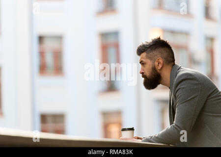 Geschäftsmann gepflegt aussehen genießen Sie Kaffee Pause aus Business Center im städtischen Hintergrund. Entspannen und erholen Sie sich. Man bärtige hipster Kaffee trinken Pappbecher. Noch ein Schluck Kaffee. Stadt Lebensstil. Stockfoto