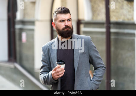 Kaffeegenuss unterwegs. Geschäftsmann gepflegt aussehen genießen Sie Kaffee Pause aus Business Center. Entspannen und erholen Sie sich. Man bärtige hipster Pappbecher Kaffee trinken. Noch ein Schluck Kaffee. Stockfoto