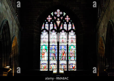 BIRMINGHAM, UK - März 2018 religiöse Symbol Glasfenster beleuchtet, die Licht im dunklen Zimmer. Ziegel Fliesen an den Wänden. Künstlerische Schnitzereien o Stockfoto