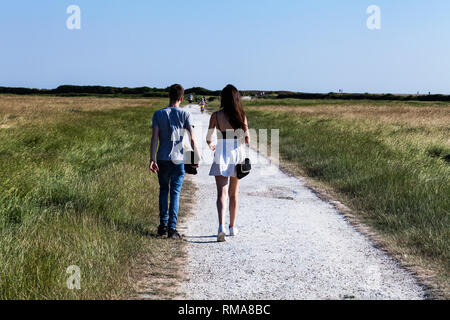 Brighton, Großbritannien - Juni 2018 Junge und Mädchen zu Fuß auf der Grünen Wiese Weg an einem sonnigen Tag. Leute, die durch den Schmutz der Straße von Landschaft Bauernhof. Grünen H Stockfoto