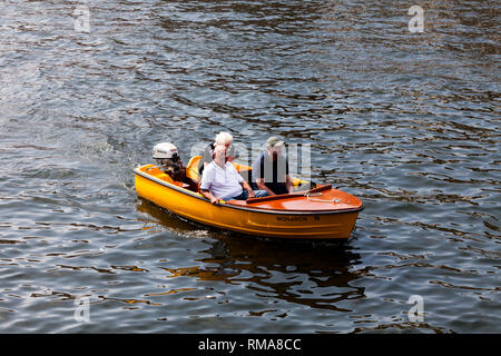 BIRMINGHAM, UK - März 2018 Menschen an Bord in kleinen offenen Motorboot auf. Orange Schiff mit Aussenborder Segeln auf welligen Wasser. Drei Erwachsene Stockfoto