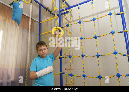 Trauriges Kind mit einem gebrochenen Arm in die häusliche Umgebung. Die Besetzung auf der Hand eines kleinen Jungen. Stockfoto