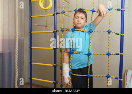 Trauriges Kind mit einem gebrochenen Arm in die häusliche Umgebung. Die Besetzung auf der Hand eines kleinen Jungen. Stockfoto