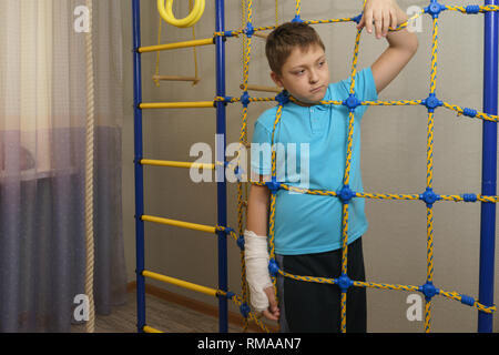 Trauriges Kind mit einem gebrochenen Arm in die häusliche Umgebung. Die Besetzung auf der Hand eines kleinen Jungen. Stockfoto