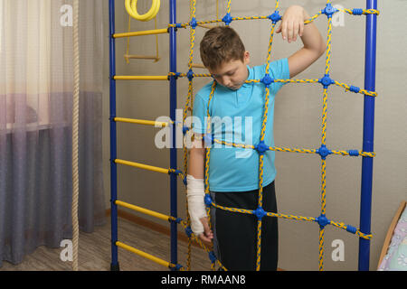 Trauriges Kind mit einem gebrochenen Arm in die häusliche Umgebung. Die Besetzung auf der Hand eines kleinen Jungen. Stockfoto