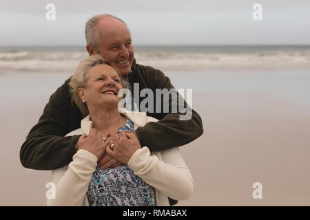 Gerne älteres Paar Umarmung stehen am Strand Stockfoto