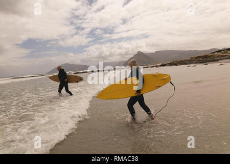 Senior Paar mit Surfbrett am Strand Stockfoto
