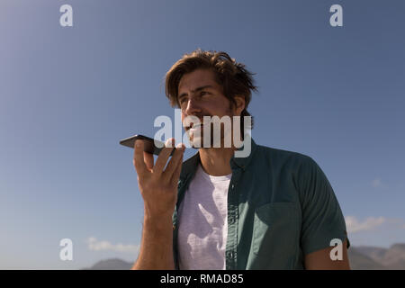 Junger Mann Gespräch am Handy am Strand Stockfoto