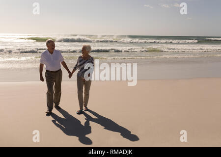 Älteres Paar Hand in Hand und zu Fuß am Strand Stockfoto