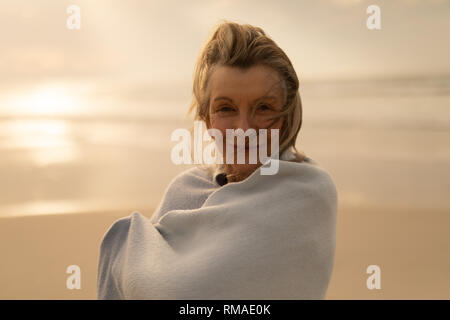 Ältere Frau in einen Schal auf den Strand gewickelt Stockfoto