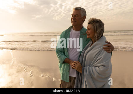 Älteres Paar umarmen einander am Strand Stockfoto