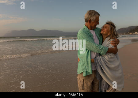 Älteres Paar umarmen einander am Strand Stockfoto