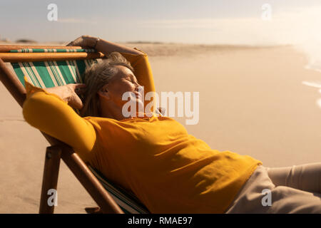 Ältere Frau schlafen auf Sonnenliege am Strand Stockfoto