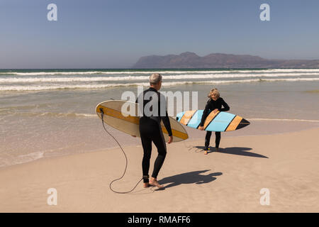 Seitenansicht der älteren surfer Paar stehend mit Surfbrett am Strand Stockfoto