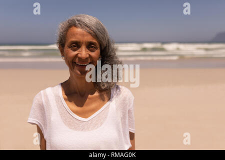 Ältere Frau an der Kamera schaut am Strand Stockfoto