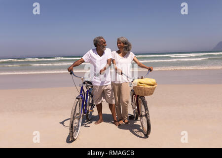 Senior Paar mit Fahrrad und suchen einander am Strand Stockfoto