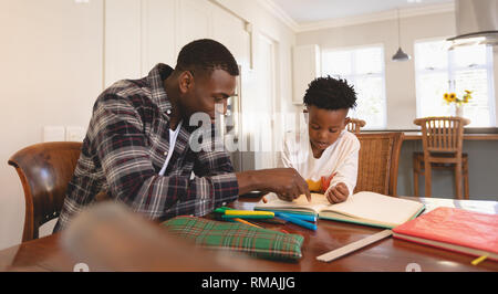 African American Vater seinen Sohn helfen bei Hausaufgaben am Tisch Stockfoto