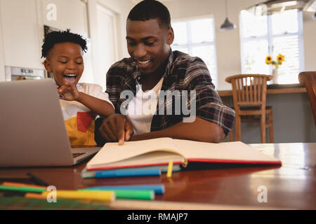 African American Vater seinen Sohn helfen bei Hausaufgaben am Tisch Stockfoto