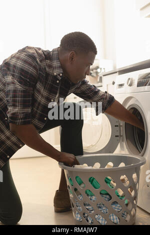 Junge afrikanische amerikanische Mann Wäsche waschen in der Waschmaschine Stockfoto