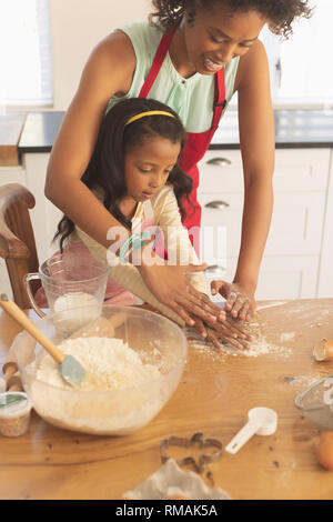 Afrikanische amerikanische Mutter und Tochter kneten den Teig in der Küche Stockfoto