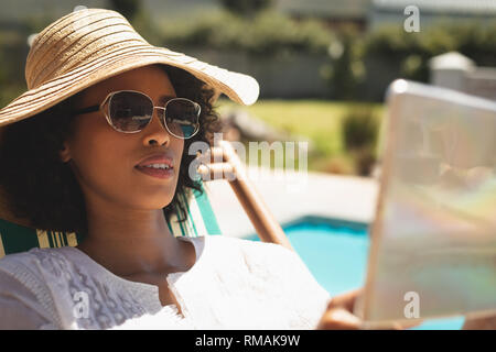 Afrikanische amerikanische Frau mit Hut und Sonnenbrille mit digitalen Tablet in Ihrem Hinterhof Stockfoto