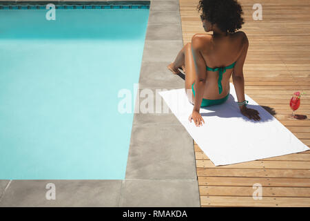 Junge afrikanische amerikanische Frau entspannend am Pool in Ihrem Hinterhof Stockfoto