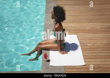 Junge afrikanische amerikanische Frau am Pool sitzen in Ihrem Hinterhof Stockfoto