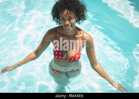Glückliche junge afrikanische amerikanische Mann an der Kamera schaut im Pool Stockfoto