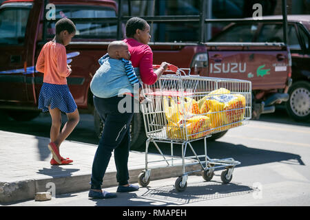 Johannesburg, Südafrika - 4 September, 2018: die Mutter mit Baby auf den Rücken drücken Warenkorb. Stockfoto