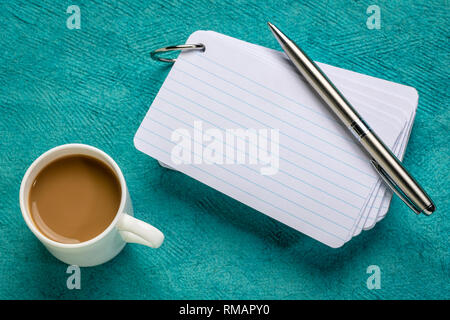 Leere Karteikarten mit einer Tasse Kaffee und einem Stift gegen strukturiertes Papier Stockfoto