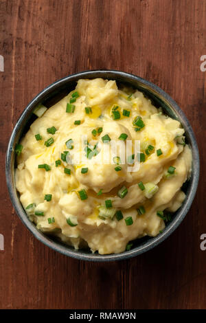 Pomme Püree, ein Foto von einer Schüssel Kartoffelpüree mit Frühlingszwiebeln, geschossen von oben auf einem dunklen Hintergrund im Landhausstil mit einem Platz für Text Stockfoto