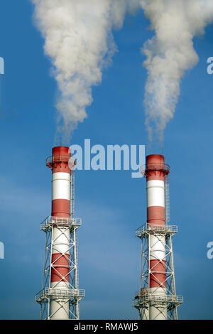 Zwei gestreifte rote und weiße Industrie Rohre mit weisser Rauch über den wolkenlosen blauen Himmel. Vorderansicht closeup Stockfoto