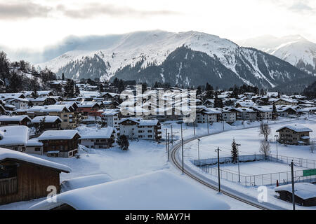 Postkarte Bild einer Schweiz, in der Nähe der Berge. Kleine Häuser mit Schnee bedeckt, die Bahn durch das Dorf zu gehen. Unglaubliche Berge Stockfoto