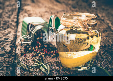 Olivenöl aromatisiert mit Zitrone und Pfefferkörner auf Holztisch, schäbige Stil Foto. Stockfoto