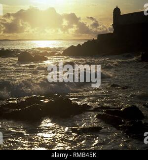 Sonnenuntergang über dem Atlantischen Ozean an der Küste von Salvador. Auf der rechten Seite, die Forte de Santa Maria Stockfoto