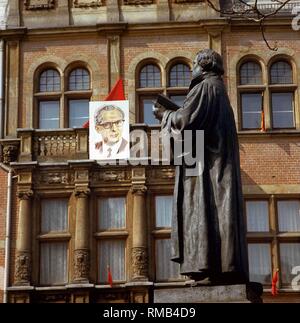 Denkmal für Martin Luther auf Zorn in Erfurt. Auf der Hausfassade im Hintergrund ist ein Portrait von Erich Honecker: Stockfoto