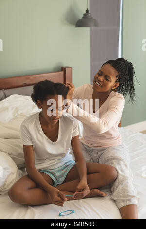 Gerne Afrikanische amerikanische Mutter Friseursalons Tochter auf dem Bett im Schlafzimmer Stockfoto