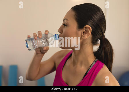Seitliche Sicht auf schöne junge Frau trinkt Wasser nach dem Workout Stockfoto