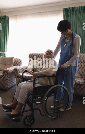 Ärztin der Interaktion mit behinderten älteren Frau im Wohnzimmer Stockfoto